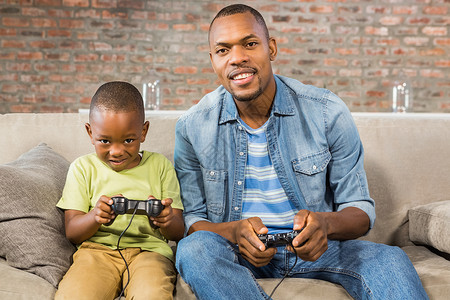 父亲和儿子一起玩电玩游戏按钮男生乐趣服装微笑家庭视频童年休闲快乐背景图片