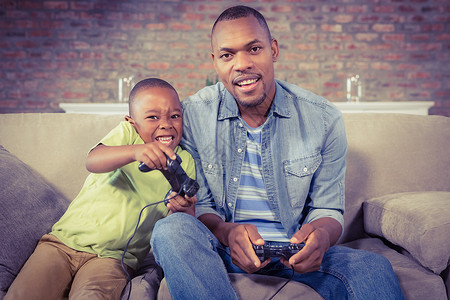 父亲和儿子一起玩电玩游戏客厅快乐童年乐趣闲暇安慰男生微笑休闲家庭生活背景图片
