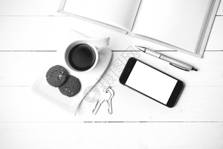 咖啡杯加饼干 手机 笔记本和主要黑白co细胞眼镜网络桌子电话工作办公室钥匙咖啡杯子背景图片