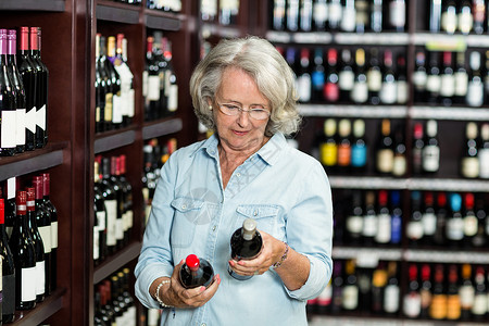 微笑的年长女子选择葡萄酒活动休闲酒精饮食服装商业闲暇消费者老年人老年背景图片
