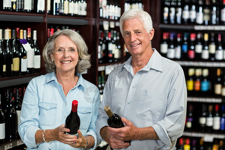 选择葡萄酒的老夫妇微笑执照男人男性夫妻顾客服装女士购物女性酒品背景图片