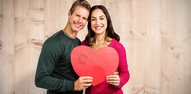 微笑的情侣握着心脏形状的相片综合图像栅栏粮食男朋友地面地板计算机木头黑发情人快乐背景图片