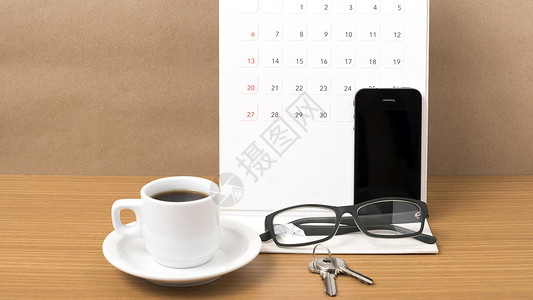 咖啡 电话 眼镜 日历和钥匙木头工作白色办公室桌子商业背景图片