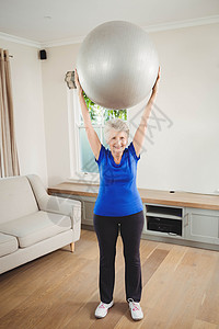高级女性在锻炼时举起球休闲家庭女士头发房子公寓住所老年人力量微笑背景图片