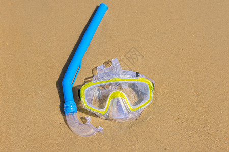 水下呼吸的游泳面罩和潜水口罩 在海滨湿沙滩上背景图片
