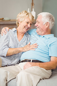 微笑的老夫妇在拥抱时互相看着对方坐着高清图片素材