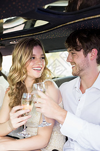 穿好衣服的夫妇 在豪华轿车上喝香槟快乐泡酒气泡长笛闲暇女士金发女郎男人长发乐趣背景图片