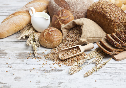 早餐 面包面包 各种小麦耳食面包和草纸牛奶产品玉米蜂蜜作品木头大麦烹饪烘烤纤维背景图片
