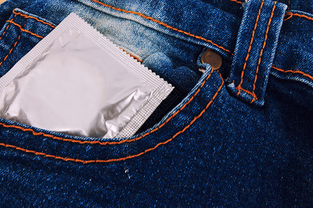 旧的蓝色牛仔裤口袋里有避孕套 专注安全套风险性别男人卫生橡皮裤子安全保健牛仔布游客背景图片