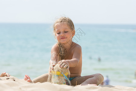 漂亮女孩在沙滩上玩了四年 在海边水桶上和一个孩子一起玩背景图片