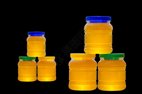黄色蜂蜜液体在黑色背景中分离的蜂蜜罐背景