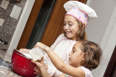 两个小女孩 一起准备蛋糕纸杯蛋糕厨师厨房围裙微笑姐妹乐趣背景图片