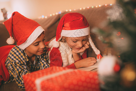 圣诞节时间家庭新年喜悦团结庆典女孩阅读姐姐兄弟水平水平的高清图片素材