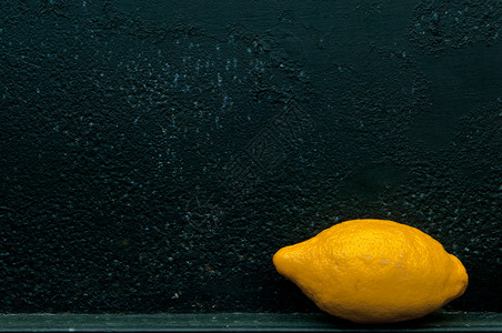 在粗糙纹理黑色背景面前的柠檬金属粮食空白水果墙纸材料帆布黄色背景图片