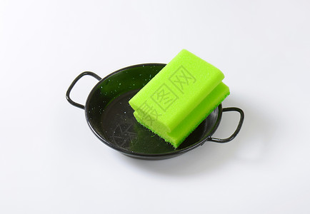 餐具上的厨房用海绵擦洗炊具黑色平底锅煎锅工具绿色背景图片