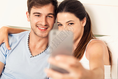 在床上做自拍的情侣卧室女士互联网技术相片摄影手机家庭女孩女性背景图片