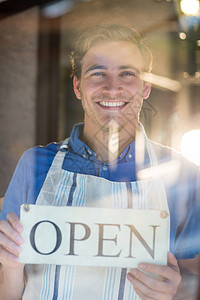 手持开放标志的微笑厨师肖像沟通工作玻璃服务男性工人餐饮制服餐厅男人背景图片