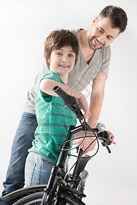 父亲和儿子笑着 带着白色的自行车背景图片