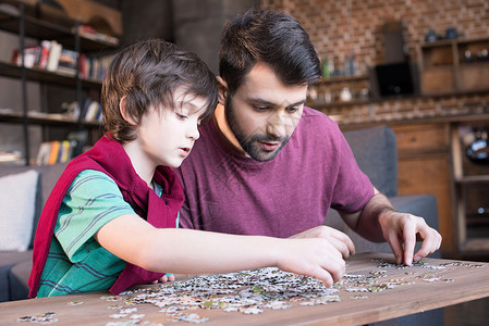 少年时代以父子为焦点的家庭游戏拼图的一面视图时代爸爸男生男人父母青春期少年儿子父亲年龄背景