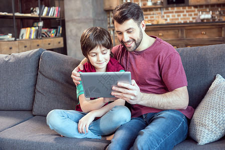 少年时代父亲和儿子在家中使用数字平板电脑微笑背景