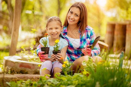 美丽的母亲和女儿小姑娘幸福家庭享受种植孩子植物园艺女士水平背景图片