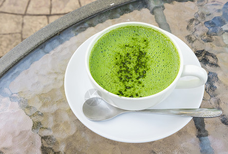 喝绿茶在玻璃桌背面加杯火辣拿铁或绿茶奶油塑料茶点食物稻草牛奶桌子营养饮料杯子背景