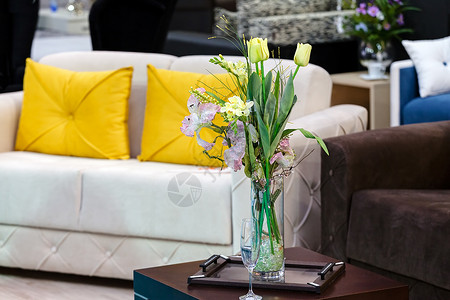 黄色枕头有花花的花瓶叶子绿色玻璃装饰棕色桌子褐色长椅枕头黄色背景