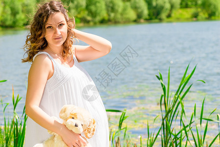 一位孕妇在附近的白沙拉风中的横向肖像腹部高清图片素材