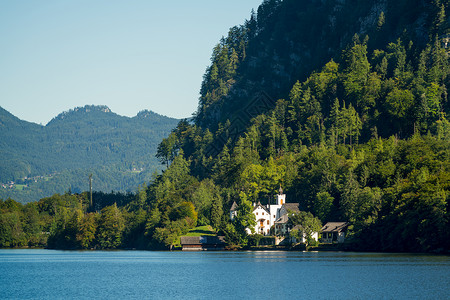 城堡哈斯穆哈斯塔特湖岸边的石岩城堡海岸线历史性地标高山山脉绿色蓝色树木房屋遗产背景