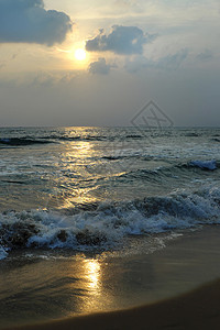 阿拉伯海日落眩光金色天空强光波浪状冲浪蓝色地平线反射阴霾背景图片