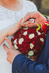 玫瑰和女人结婚戒指和新娘和新郎的手 新婚夫妇在仪式上 婚姻 恋爱中的男人和女人 两个快乐的人庆祝成为一家人庆典胸花婚礼女士家庭夫妻玫瑰传统背景