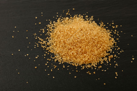 一片棕色甘蔗糖洒在黑板上黄色勺子食物营养黑色颗粒状水晶烹饪石板美食背景图片