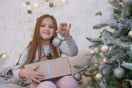 圣诞树下的女孩与球玩具展示惊喜女儿礼物派对幸福家庭孩子喜悦背景图片