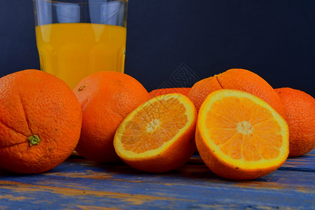 橘子 橙子 一杯橙汁和蓝木本底的手工柑橘饼 橙子切成两半材料吸管水果液体厨房果汁橙色铰刀早餐橘子汁背景