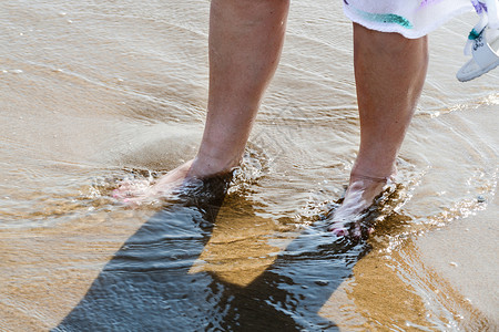 间歇性跛行海滩散步 女人的腿在水中背景
