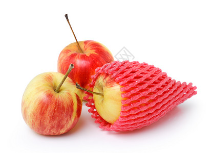 在一个泡沫网袖中的苹果中 在白色上隔开天鹅绒水果粉红色黄色水果套皮肤红色缓冲包装粉色背景图片