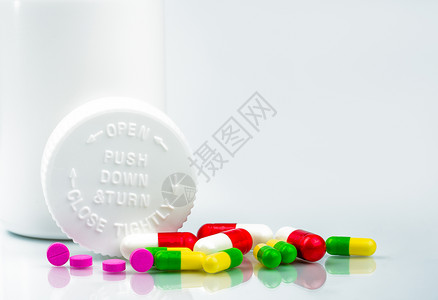 白色背景上的彩色药丸和带有空白标签和复制空间的儿童安全瓶 医院概念中的药学部 药店概念 医药行业 药房背景 药理学和药物相互作用背景图片