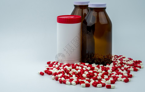 五颜六色的抗生素胶囊药丸与白色背景上的三个瓶子 耐药性 抗生素用药合理搭配 医药行业 药房背景 抗生素药物滥用 卫生预算和政策背景图片