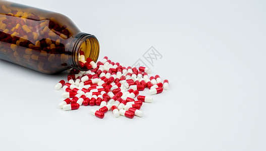 五颜六色的抗生素胶囊药片与两个琥珀色玻璃瓶隔离在白色背景 耐药性 抗生素用药合理搭配 医药行业 药房背景 抗生素药物滥用 卫生预背景图片