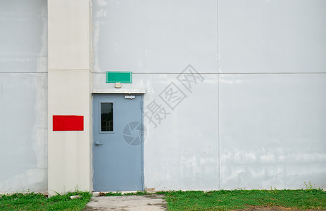 封闭的灰色门 白色混凝土墙上有绿色和红色文字盒 有复制空间入口工厂抑制仓库建筑学建筑水泥背景图片