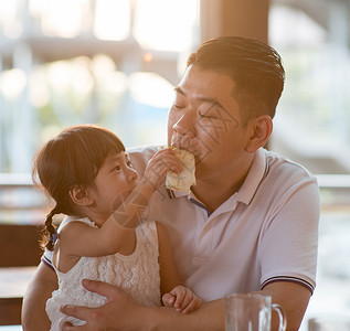 女孩喂食爸爸面包甜的高清图片素材