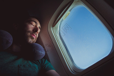 长着脖子枕头的年轻人休息和睡在飞机上高清图片