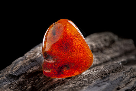红色的石头天然琥珀 一块黄色和红色半透明的天然琥珀 放在一块石头上琥珀色蜂蜜材料宝藏太阳石反射裂缝宏观珠宝化石背景