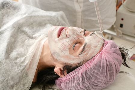 在美容院的年轻女子 确实恢复了活力 将程序Darsonval在脸上按摩沙龙护理药品激光硬件治疗女性美容师女士皮肤科高清图片素材