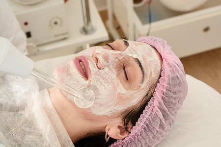 在美容院的年轻女子 确实恢复了活力 将程序Darsonval在脸上温泉塑料激光按摩器按摩护理治疗皮肤皱纹美容师皮肤护理高清图片素材