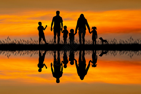 日落时 幸福的全家环绕着月光妈妈反射男生孩子们父亲快乐母亲女孩草地孩子背景图片