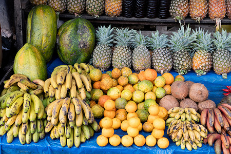 在一个市场上销售当地产品香蕉水果菠萝橙子椰子木瓜街道杂货西瓜背景图片