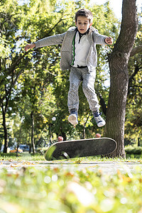 拿滑板男孩带滑板的男孩树叶街道长板闲暇木板滑冰青少年娱乐溜冰者公园背景