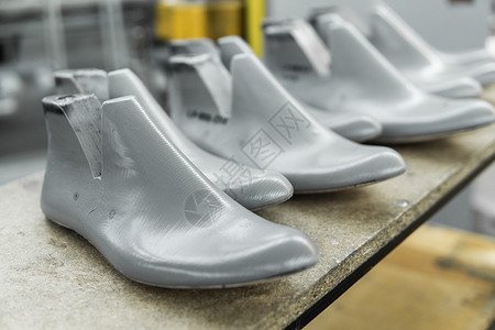 刀具设计素材塑料鞋楦用于制鞋 用于制造现代鞋的塑料鞋楦行 木架子上有很多塑料鞋楦 用于鞋子设计的设备创造力工厂皮匠刀具工具产品工作网格解剖学背景
