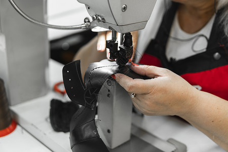 皮革车间的缝纫机在用手处理鞋子的皮革细节 女鞋厂有缝纫机的手机器生产衣服纺织品行动接缝裁缝拉链工艺缝纫家具高清图片素材